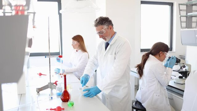 Mature scientist and his team working at the laboratory