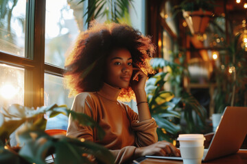 Beautiful black woman is sitting at the cafe with laptop, freelancer, remote work