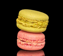 Two sweet macarons, macro, isolated on black background.
