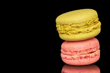 Two sweet macarons, macro, isolated on black background.