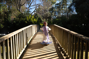 A pretty girl dancing flamenco in a typical gypsy dress with frills and fringes walks on a wooden...