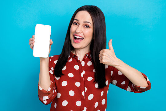 Photo portrait of attractive woman hold gadget show white screen thumb up wear trendy dotted red clothes isolated on blue color background