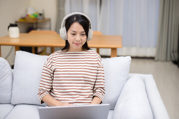 Housewife with headphone and work on notebook computer at home - 758112809
