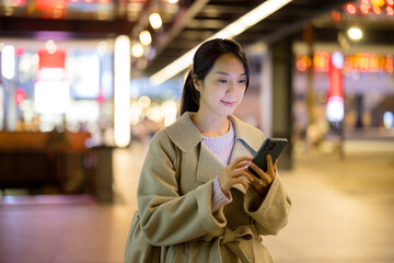 Businesswoman look at the mobile phone in city at night - 758113265