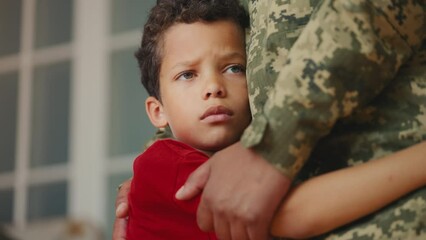 Sad boy hugs his dad in uniform, saying goodbye to father leaving for military