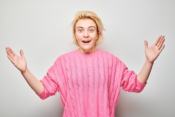 Portrait blond young woman happy face smiling joyfully with raised palms and shocked open mouth...