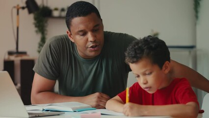 Supportive African American dad helps his son with school homework, family bond