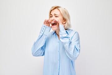 Portrait of blonde girl shouting loudly with hands, news, palms folded like megaphone isolated on...
