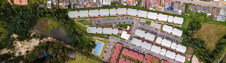 Panorámica aérea tomada en Colombia. Urbanización popular con acceso a montaña y lago - obrazy, fototapety, plakaty