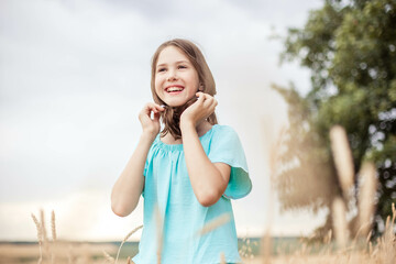 Adorable teenage girl looking at the sky outdoors on the background of the sky, close-up, copy space