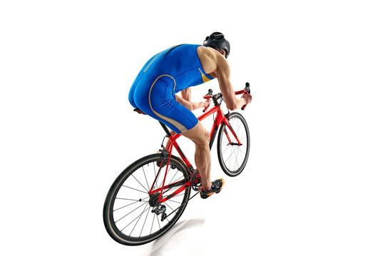 Back view image of concentrated sportsman in blue sportswear and helmet in motion on bike isolated on white studio background. Concept of sport, active and healthy lifestyle, speed, endurance, hobby