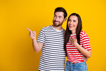 Photo portrait of nice young couple hug point look amazed empty space wear trendy striped outfit isolated on yellow color background
