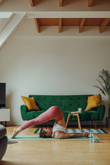Woman in sportswear doing yoga pose on wood flooring in living room