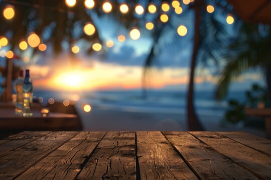 Empty wooden planks table against a blurred background with a sea coast with palm trees and glowing light bulbs in the evening