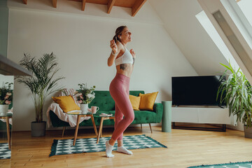 Woman dancing in living room with green couch in backdrop