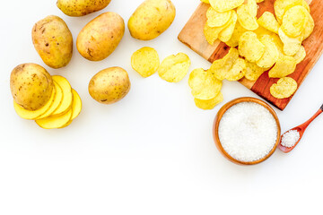 Homemade low calorie potato chips with raw potatoes on board, top view