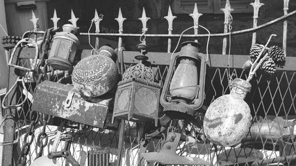 Collection of old utensils. Rust and peeling paint. Lanterns and flags are hanging on the fence....