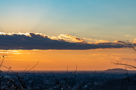 vista dettagliata di un'area in pianura in Friuli Venezia Giulia, di sera, con un bellissimo cielo parzialmente nuvoloso al tramonto, in inverno, con sfumature tra l'azzurro e l'arancione