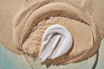 A smear of white sunscreen with SPF against a background of sand.