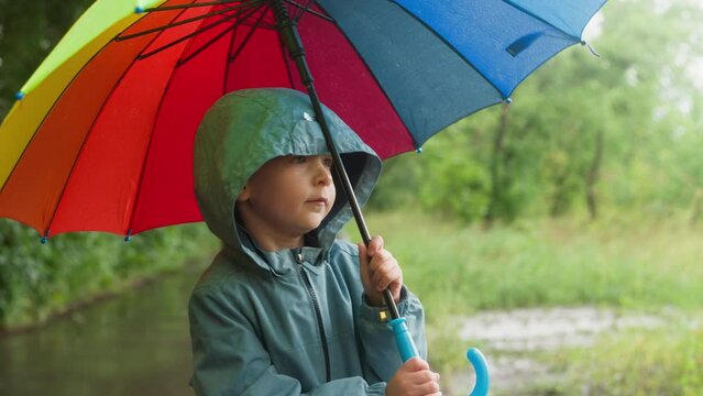 Kid shelters beneath umbrella in park