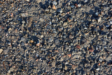 Nature, minerals, granite, gray stones and crumbs, red small bricks scattered all over the sandy surface of the earth.