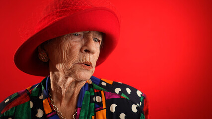 Funny fisheye of elderly senior old woman with wrinkled skin wearing red hat gives great idea...