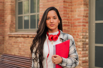 Close up individual portrait of a pretty hispanic female student with serious expression looking at...