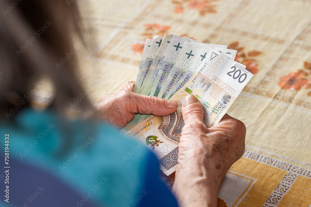 Wall mural polish old woman holds a pension in her hands, economic concept, home budgets of pensioners in polan