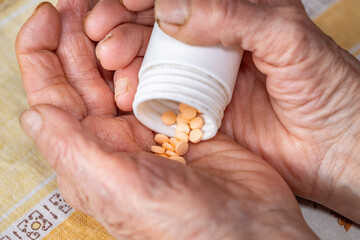 Elderly Woman's Hands and Orange Pills, Health Concept, Medicines Related to Older People's...
