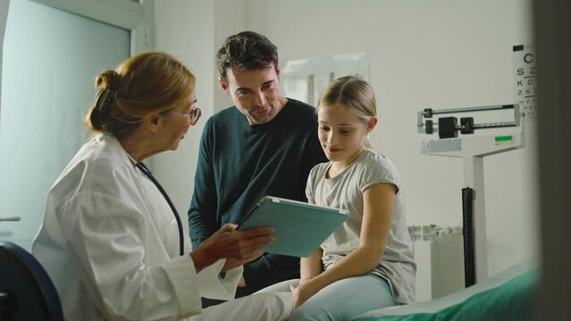 In a clinic or hospital, a doctor does a health check up on a little girl accompanied by her father.
Medicine and prevention concept
