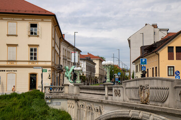 Ljubljana, Slovenia;  The Ljubljana Dragon Bridge spans the Ljubljanica River, Ljubljana Central Market and Saint Nicholas's Cathedral (Katedrala Sv. Nikolaj), dragon sculpture