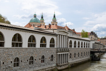 Ljubljana, Slovenia;  The Ljubljana Dragon Bridge spans the Ljubljanica River, Ljubljana Central Market and Saint Nicholas's Cathedral (Katedrala Sv. Nikolaj), dragon sculpture