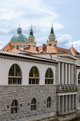 Fototapeta premium Ljubljana, Slovenia; The Ljubljana Dragon Bridge spans the Ljubljanica River, Ljubljana Central Market and Saint Nicholas's Cathedral (Katedrala Sv. Nikolaj), dragon sculpture