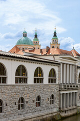 Ljubljana, Slovenia;  The Ljubljana Dragon Bridge spans the Ljubljanica River, Ljubljana Central Market and Saint Nicholas's Cathedral (Katedrala Sv. Nikolaj), dragon sculpture