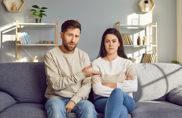 Family couple discussing relationship problems in online therapy. Young man and woman sitting in front of camera on couch at home, having remote therapy session, talking about their misunderstandings