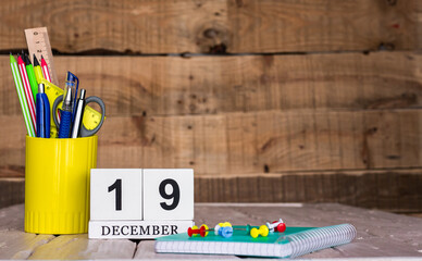 December calendar background with number  19. Stationery pens and pencils in a case on a wooden...