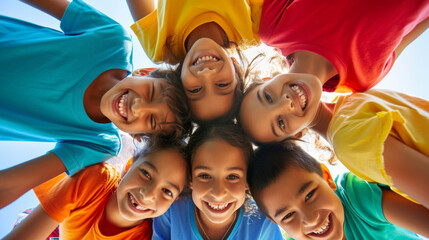 Fototapeta premium High-angle shot of a group of children forming a circle and looking up towards the camera with smiling faces.