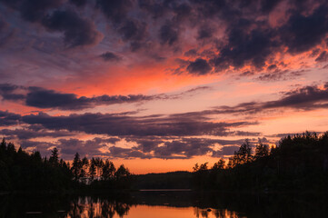 Obraz premium Vibrant Sunset Over a Calm Lake in Sweden With Dramatic Clouds