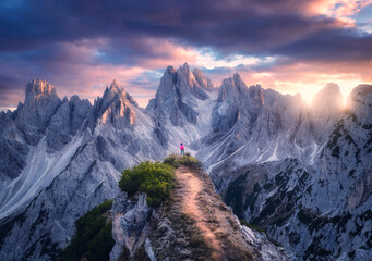 Aerial view of girl on the mountain peak and rocks at colorful sunset in summer. Tre Cime, Dolomites, Italy. Top drone view of woman on trail, cliffs, grass, sky, clouds, sunlight in spring. Hiking - 758213063