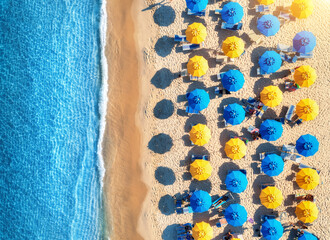 Aerial view of yellow and blue umbrellas on white sandy beach, people in sea at sunset in summer. Beach, Sardinia, Italy. Tropical landscape with azure water. Travel and vacation. Top view of seaside - 758213275