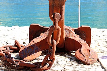 Old rusty anchor with chain on the pier