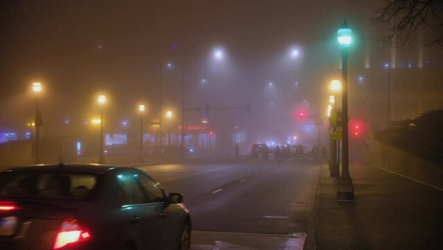 Cars drive on empty road of fog night time. Chicago street. Slow motion