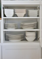 Kitchen dish cabinet neatly organized with family dishes and crockery. Photo concept, home life,...