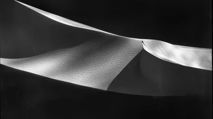 Foto op Canvas  a black and white photo of a sand dune with a long white ribbon hanging from the top of the dune. © Jevjenijs