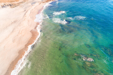shore of a beach with turquoise waters seen from a drone.