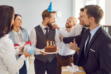 Group of young smiling business people coworkers congratulating colleague man with birthday. Male...
