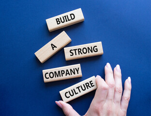 Company culture symbol. Wooden blocks with words Build a strong company culture. Beautiful deep blue background. Businessman hand. Business and Company culture concept. Copy space.