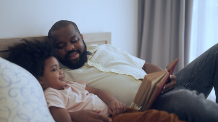 father reading a story book with son