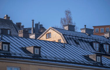 Facades and frosty tin roof with dorms and chimneys in the district Mariaberget, a sunny winter day...