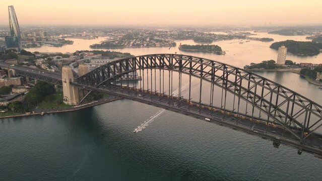Aerial drone flyover view of Sydney Harbour Bridge, NSW Australia showing two trains crossing the bridge during an early morning sunrise in March 2024 
